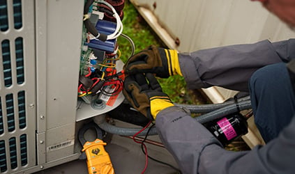 Technician repairing outdoor HVAC unit wiring Technician repairing outdoor HVAC unit wiring