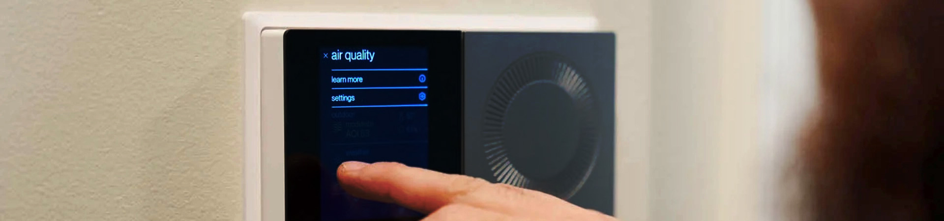 A customer adjusting settings on their smart thermostat in their home.