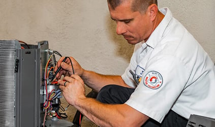 George Brazil HVAC technician repairing outdoor HVAC unit wiring George Brazil HVAC technician repairing outdoor HVAC unit wiring