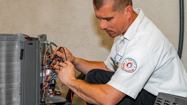 HVAC technician running diagnostics George Brazil HVAC technician running diagnostic testing on an AC unit.